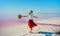 Happy smiling woman in red skirt dancing, dynamic moving at salt flats of pink lake