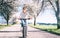 Happy smiling woman rides a bicycle on the country road under bl