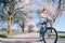 Happy smiling woman rides a bicycle on the country road under blossom trees. Spring is comming concept image