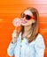 Happy smiling woman in sunglasses with sweet lollipop over colorful orange background