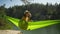 happy smiling woman swinging in hammock on lake shore in forest. wanderlust, summer vacation, travel outdoors, active