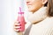 Happy smiling woman in woollen sweater holding bottle with pink homemade strawberry or cherry milkshake