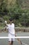 Happy and smiling young amateur tennis player looking to camera winning an award. Holding a cup on his hand