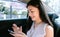 Happy smiling young Asian woman in casual clothing using smart phone in sitting back seat in urban city. Transportation, vehicle,