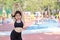 Happy smiling young beautiful asian woman in sportswear relaxing at public exercise machine. Cute and sporty girl listen music via