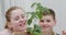 Happy smiling young brother and sister admiring a green leafy plant that they have just transplanted into a wooden box