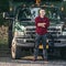 Happy smiling young farmer man standing in front of pickup truck ready to work.