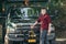 Happy smiling young farmer man standing in front of pickup truck ready to work.