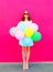 Happy smiling young woman with an air colorful balloons having fun in summer over a pink background