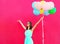 Happy smiling young woman with an air colorful balloons is having fun in summer over a pink background