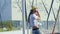 Happy smiling young woman having fun on chain swing on playground at park