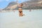 Happy smiling young woman is jumping on the beach. Concept of friendly family. Happy summer days. Balos Lagoon. Elafonisi Beach -