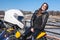 Happy and smiling young woman motorcyclist sitting on back of motorcycle, passenger of rider, white helmet on a foreground