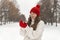 Happy smiling young woman in red knitted hat and mittens,alley in winter park. Portrait of pretty girl in woolen sweater