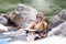 Happy solo woman traveller reading map while sitting on chair at waterfall