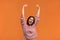 Happy sound.Energized happy woman in pink knitted sweater raises hands joyfully, being in high spirit, jumps playfully, dances to