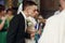 Happy spiritual couple, stylish groom and beautiful brunette bride in white dress holding candles at wedding church ceremony