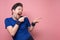 Happy sportsman pointing with finger on pink wall with copyspace