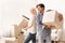 Happy Spouses Holding Moving Boxes Standing In New House