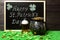 Happy St. Patricks Day chalk lettering on blackboard, mug of beer, leprechauns pot of gold treasure and shamrock leaves and coins