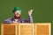 Happy St Patricks Day. Fat funny bearded man hat points a finger at green Patrick`s day background