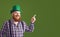 Happy St Patricks Day. Fat funny bearded man hat points a finger at green Patrick`s day background