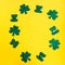 Happy St. Patrickâ€™s Day. Frame of three leaf clovers on bright yellow background.