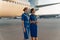 Happy stewardesses posing against the backdrop of an airplane before flight