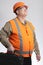 Happy stout man in hard hat and reflective vest and protective glasses on grey background, builder holding tool in case