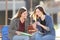 Happy students checking smart phone on a bench