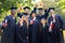 Happy students in mortar boards with diplomas