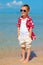 Happy stylish boy standing in water on tropical beach