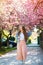 Happy stylish girl in spring. Women fashion. Woman enjoying amazing sakura blooming tree