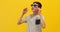 Happy stylish teen guy in sunglasses standing on a yellow background