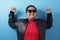 Happy success fat Asian boy wearing leather jacket and sunglasses shows winning gesture