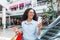 Happy and successful woman shopping for clothes in a supermarket store, Hispanic woman holding a smartphone reading