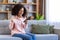 Happy and successful woman winner got good achievement result, african american woman sitting on sofa in living room at