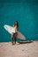 Happy surfer girl with surfboard in front of blue wall