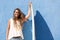 Happy surfer girl with surfboard in front of blue wall