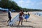 Happy surfers with surfboards along the sea shore going into the sea