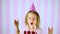 Happy surprise, close eyes little girl in pink cap blowing out candles on a birthday chocolate cake