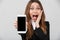 Happy surprised lady showing smartphone with blank screen and looking camera