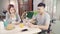 Happy sweet Asian couple man in a wheelchair having breakfast, cereal in milk, bread and drinking orange juice.