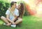 Happy sweet young couple teenagers sitting on the grass in summer