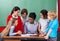 Happy Teacher Teaching Schoolchildren At Desk In