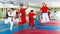 Happy team of karate students together with female trainer in jump after gym