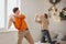 Happy teen couple having fun fighting with pillows on bed in New Years festively decorated bedroom