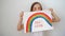 Happy teen girl drew rainbow and poster stay home.