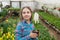 happy teen girl florist care pot plants in greenhouse, gardener