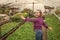 happy teen girl florist care pot plants in greenhouse, gardener